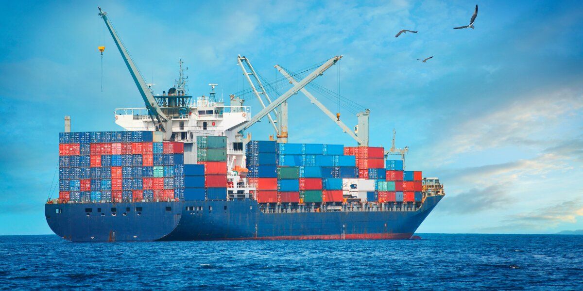 Loaded container ship sailing under a clear sky